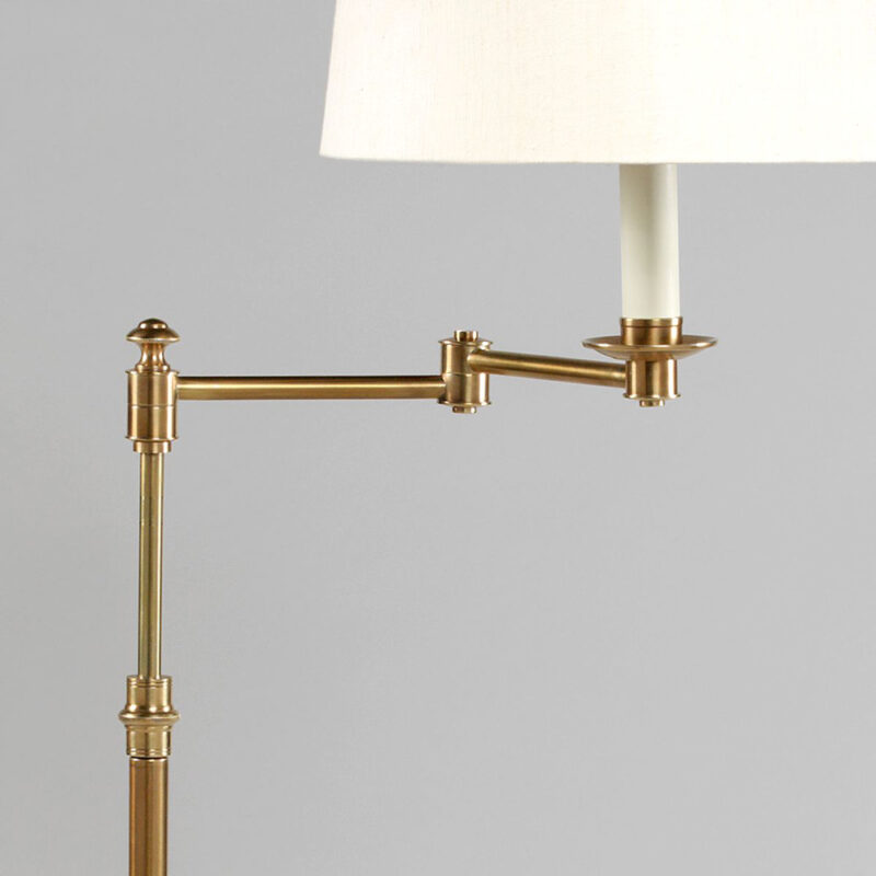 Detaljbilde av gulvlampe med lampefot i messing med bevegelig arm, og med hvit lampeskjerm i lin