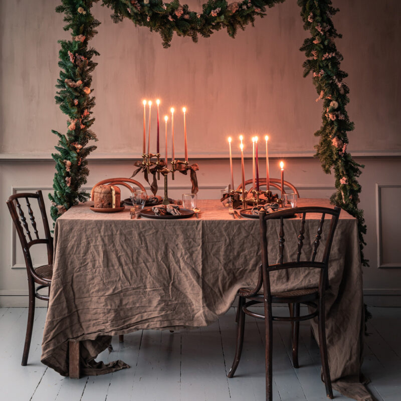 Mange lysestaker i messing fra stoff nagel er stablet på hverandre og står på en dekket julebord