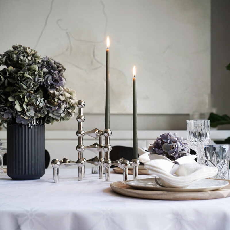 Mange lysestaker i krom fra stoff nagel er stablet på hverandre og står på et bord
