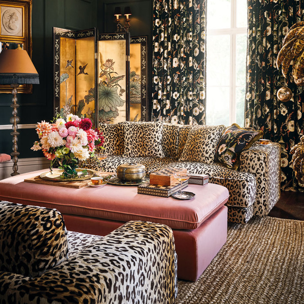 To sofaen i leopardmønster stående i en stue fylt med tekstiler og mønstre.