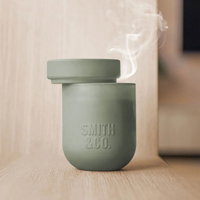 duftlys i grønn beholder med duften amber og freesia fra smit & Co.